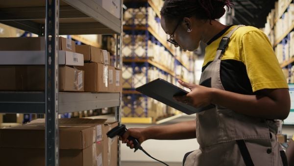 Image of a woman using a barcode scanner and mobile computer to take inventory in a warehouse