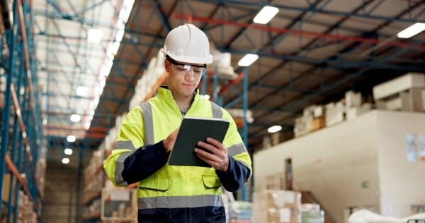 Woman in a distributor warehouse using a tablet connected to an AIDC system
